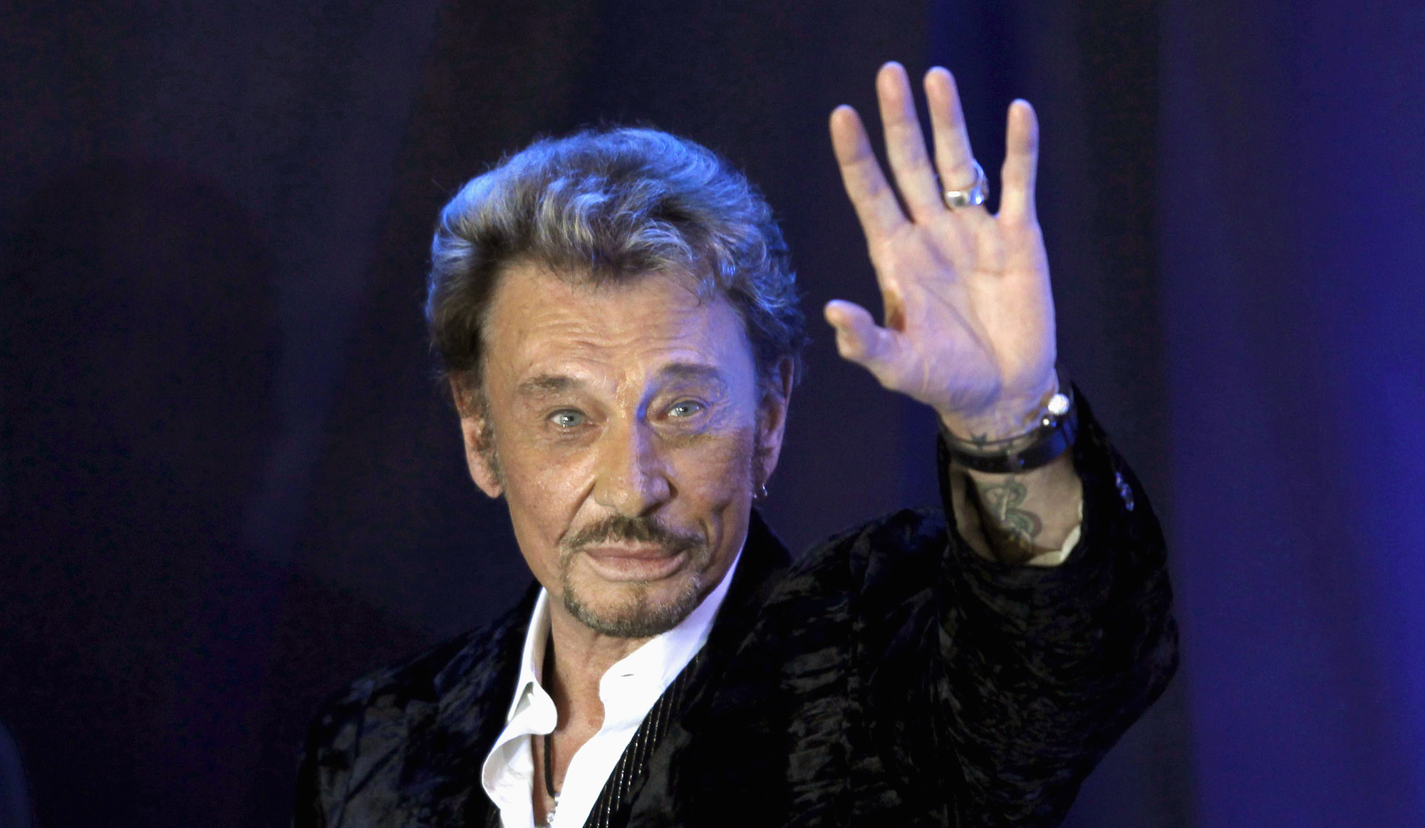 French singer Johnny Hallyday waves to fans attending a ceremony to promote his new album "Jamais seul" (Never alone) at the Virgin Megastore in Paris early March 28, 2011. REUTERS/Charles Platiau ( FRANCE - Tags: ENTERTAINMENT) - RTR2KHTG